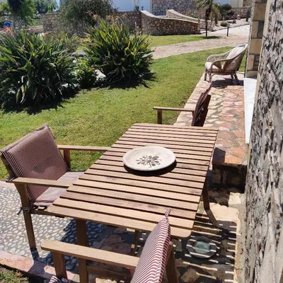 a wooden table with two chairs and a plate on it at Kiotari Stone House in Gennadi