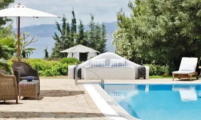 a swimming pool with chairs and an umbrella next to it at Villa Blue Sapphire in Pefki Rhodes