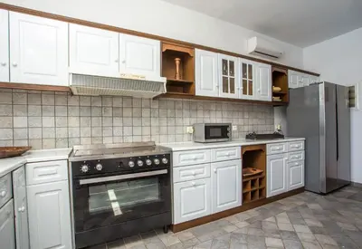 a kitchen with white cabinets and a stainless steel refrigerator at Villa Blue Sapphire in Pefki Rhodes