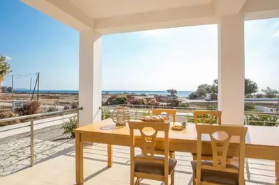 a dining room with a table and chairs on a balcony at Kelly's Beach House 2 in Gennadi