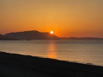 a sunset on the beach with the sun setting at Kelly's Beach House 2 in Gennadi