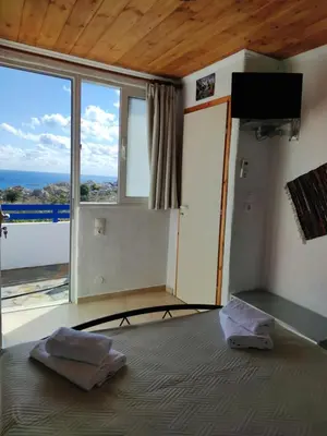 a bedroom with a bed with a view of the ocean at Ioli's Apartments in Archangelos