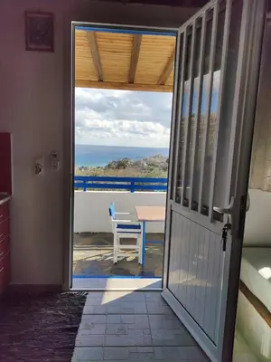 a door to a balcony with a table and a view of the ocean at Ioli's Apartments in Archangelos