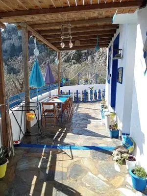 a patio with a table and umbrellas on a building at Ioli's Apartments in Archangelos
