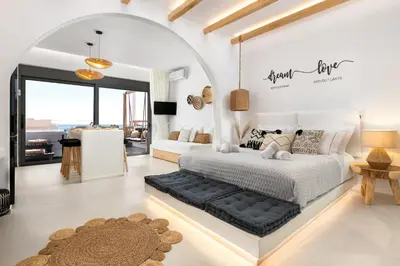 a bedroom with a white bed with a black seat at Pefkos Allure Luxury Suites with Jacuzzi in the heart of Pefkos!!! in Pefki Rhodes