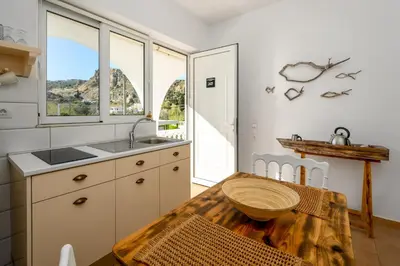a kitchen with a wooden table and a sink at Afroditi Superior Apartments in Archangelos