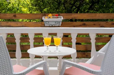 two glasses of orange juice sitting on a table on a patio at Afroditi Superior Apartments in Archangelos