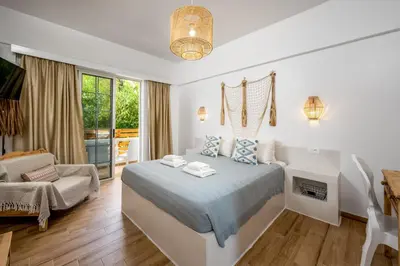 a white bedroom with a bed and a fireplace at Afroditi Superior Apartments in Archangelos