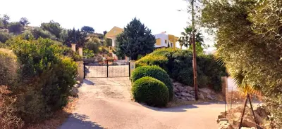 a house with a gate on a dirt road at Villa Irene Lindos, Lindos 10 mins, Beach 4 mins, Amazing Views 0 mins in Kalathos