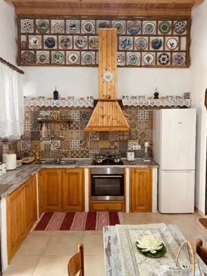 a kitchen with wooden cabinets and a white refrigerator at Archangelos Family House in Archangelos