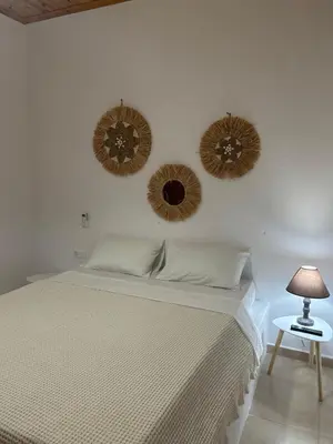 a bedroom with a bed and three mirrors on the wall at Archangelos Family House in Archangelos