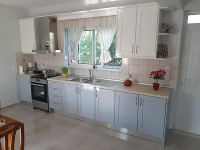 a kitchen with white cabinets and a sink and a window at Katerina Villa In Kiotari in Kiotari