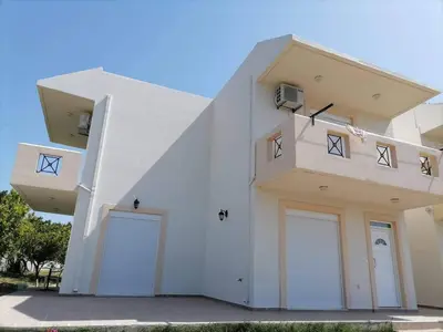 a white house with two garage doors on it at Katerina Villa In Kiotari in Kiotari