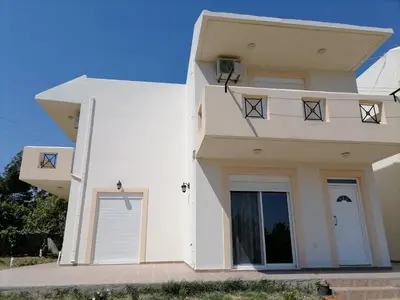a white house with two garage doors at Katerina Villa In Kiotari in Kiotari