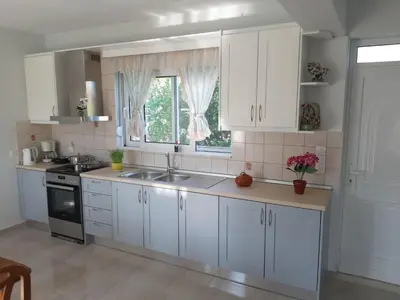 a kitchen with white cabinets and a sink and a window at Katerina Villa In Kiotari in Kiotari