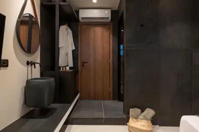 a bathroom with a toilet and a wooden door at Lindian Plumeria in Líndos
