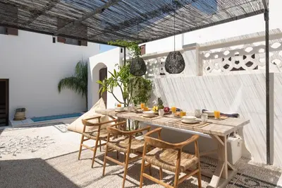 a patio with a wooden table and chairs at Lindian Plumeria in Líndos