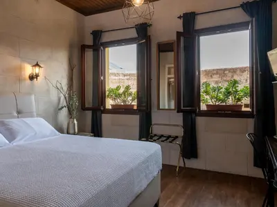 a bedroom with a bed and two windows with potted plants at Casa Theano - Old Town in Rhodes Town