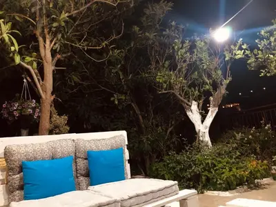 a white bench with blue pillows in a garden at night at Electra in Líndos