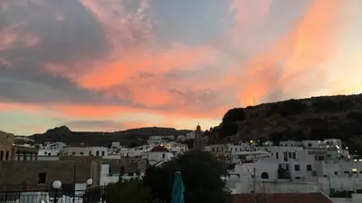 a sunset over a city with white buildings at Electra in Líndos
