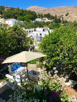 an umbrella and chairs and flowers in front of a town at Electra in Líndos