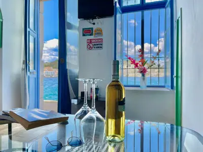 a bottle of wine sitting on a glass table at Seafront - Harbour view , Pitini 2 in Symi
