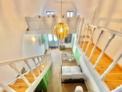 a room with a staircase with a couch and a chandelier at Seafront - Harbour view , Pitini 2 in Symi