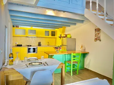 a kitchen with yellow cabinets and a table and chairs at Seafront - Harbour view , Pitini 2 in Symi