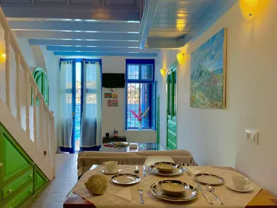 a dining room with a table and chairs and a staircase at Seafront - Harbour view , Pitini 2 in Symi
