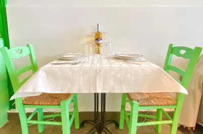 a table with a white table cloth on it with green chairs at Seafront - Harbour view , Pitini 1 in Symi