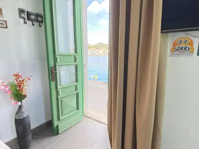 a green door with a view of the ocean at Seafront - Harbour view , Pitini 1 in Symi
