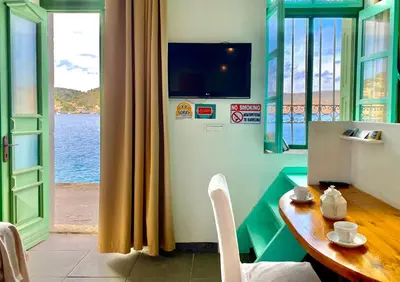 a dining room with a table and a view of the water at Seafront - Harbour view , Pitini 1 in Symi