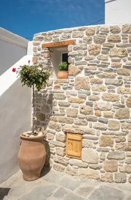 a stone wall with a window and a plant in a pot at Anastasia Traditional House in Lardos