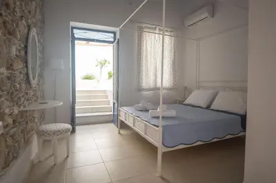 a white bedroom with a bed and a window at Anastasia Traditional House in Lardos