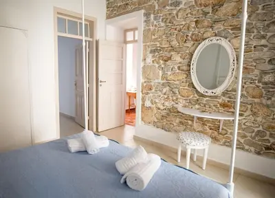 a bedroom with a blue bed and a stone wall at Anastasia Traditional House in Lardos