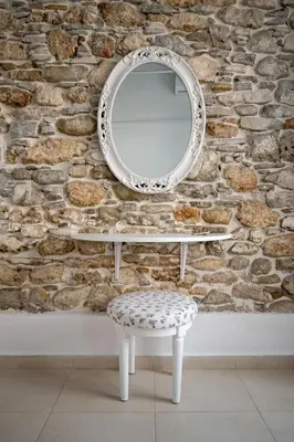 a mirror and a stool in front of a stone wall at Anastasia Traditional House in Lardos