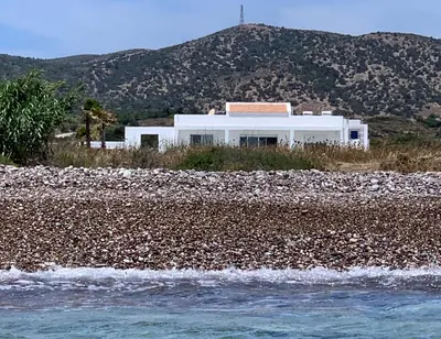 a white house on the shore of a rocky beach at Seashore Villa - Luxury Beachfront - Pool & Sea View in Lachania