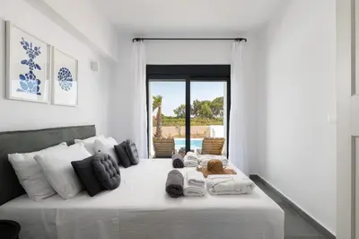 a bedroom with a large white bed with white pillows at Seasand Villa - Luxury Pool Retreat - 150m Beach in Lachania