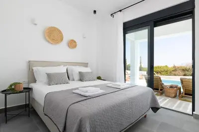 a white bedroom with a bed and a balcony at Seasand Villa - Luxury Pool Retreat - 150m Beach in Lachania