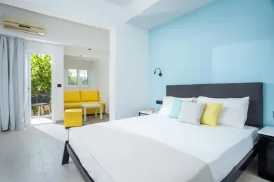a bedroom with a large bed and a yellow chair at Faliraki Premium Hotel in Faliraki