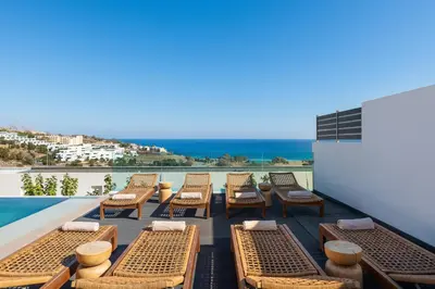 a patio with lounge chairs and a swimming pool at Villa Rocabella with heated pool & jacuzzi in Lindos in vlicha