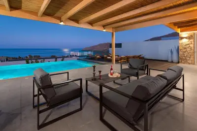 a living room with a table and chairs and a swimming pool at Villa Rocabella with heated pool & jacuzzi in Lindos in vlicha