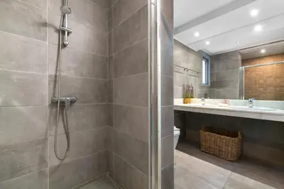 a bathroom with a shower and a toilet and a sink at Villa Rocabella with heated pool & jacuzzi in Lindos in vlicha