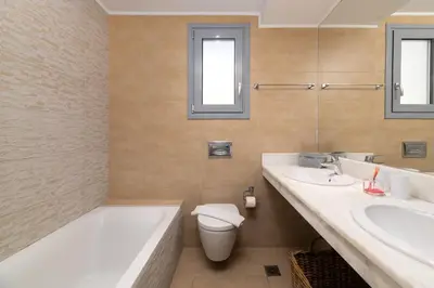 a bathroom with a tub and a toilet and a sink at Villa Rocabella with heated pool & jacuzzi in Lindos in vlicha