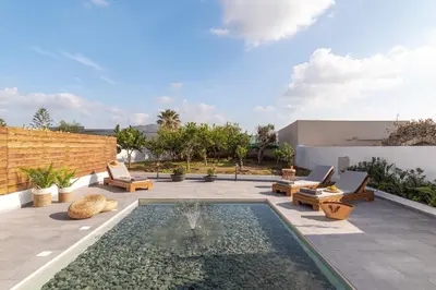 a patio with a pool with chairs and a fountain at Giorgio Deluxe Studio in Kattavía