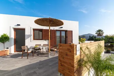 a patio with a table and an umbrella at Giorgio Deluxe Studio in Kattavía
