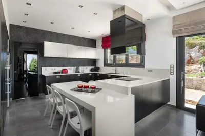 a kitchen with white countertops and a large island with stools at Villa La Bianca in Koskinou