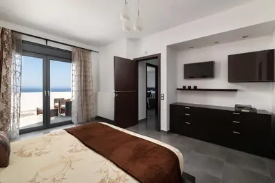 a bedroom with a large bed and a large window at Villa La Bianca in Koskinou
