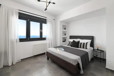 a bedroom with a bed and a large window at Villa La Bianca in Koskinou
