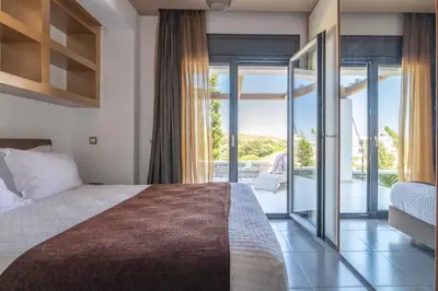 a bedroom with a large bed and a balcony at Villa La Bianca in Koskinou
